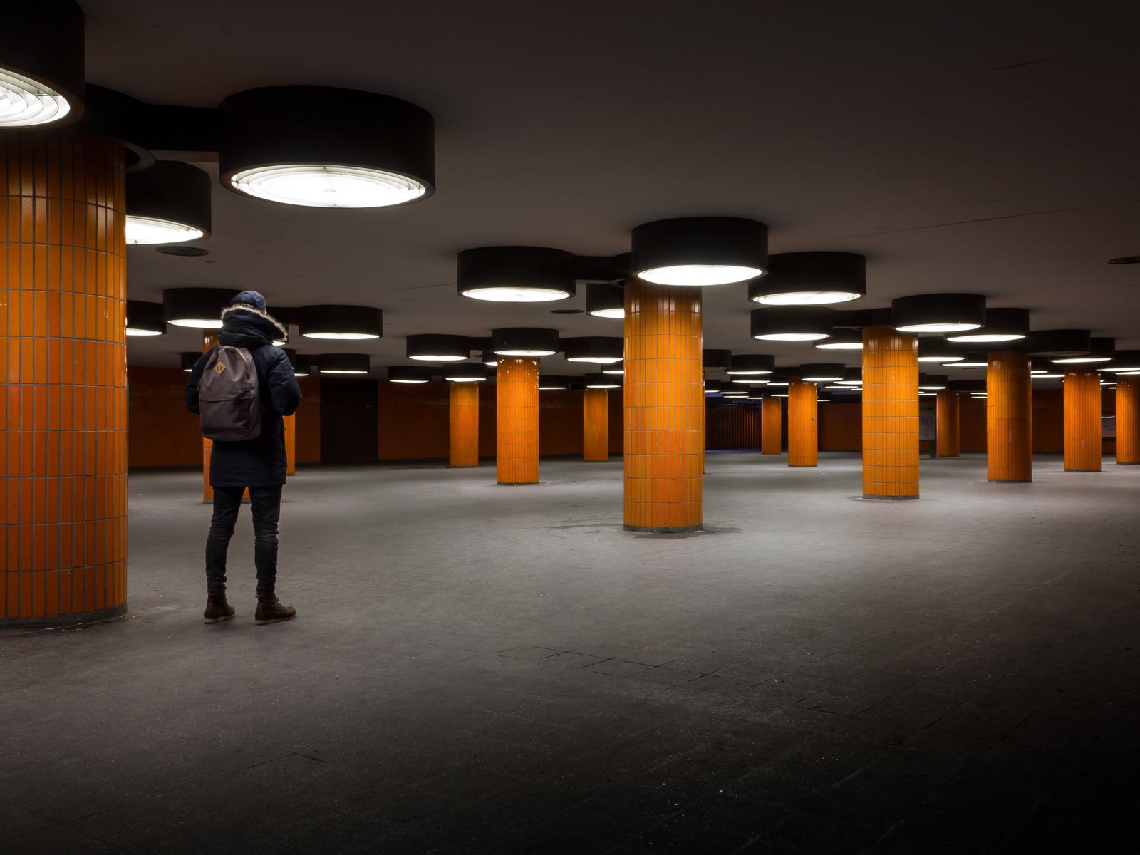 A person with a backpack in a large, modern hall