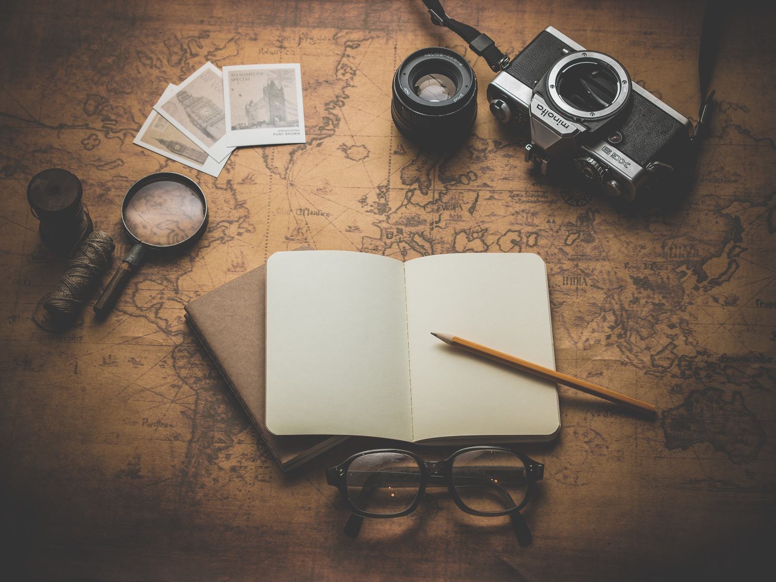 A notebook, glasses and magnifier on a desk